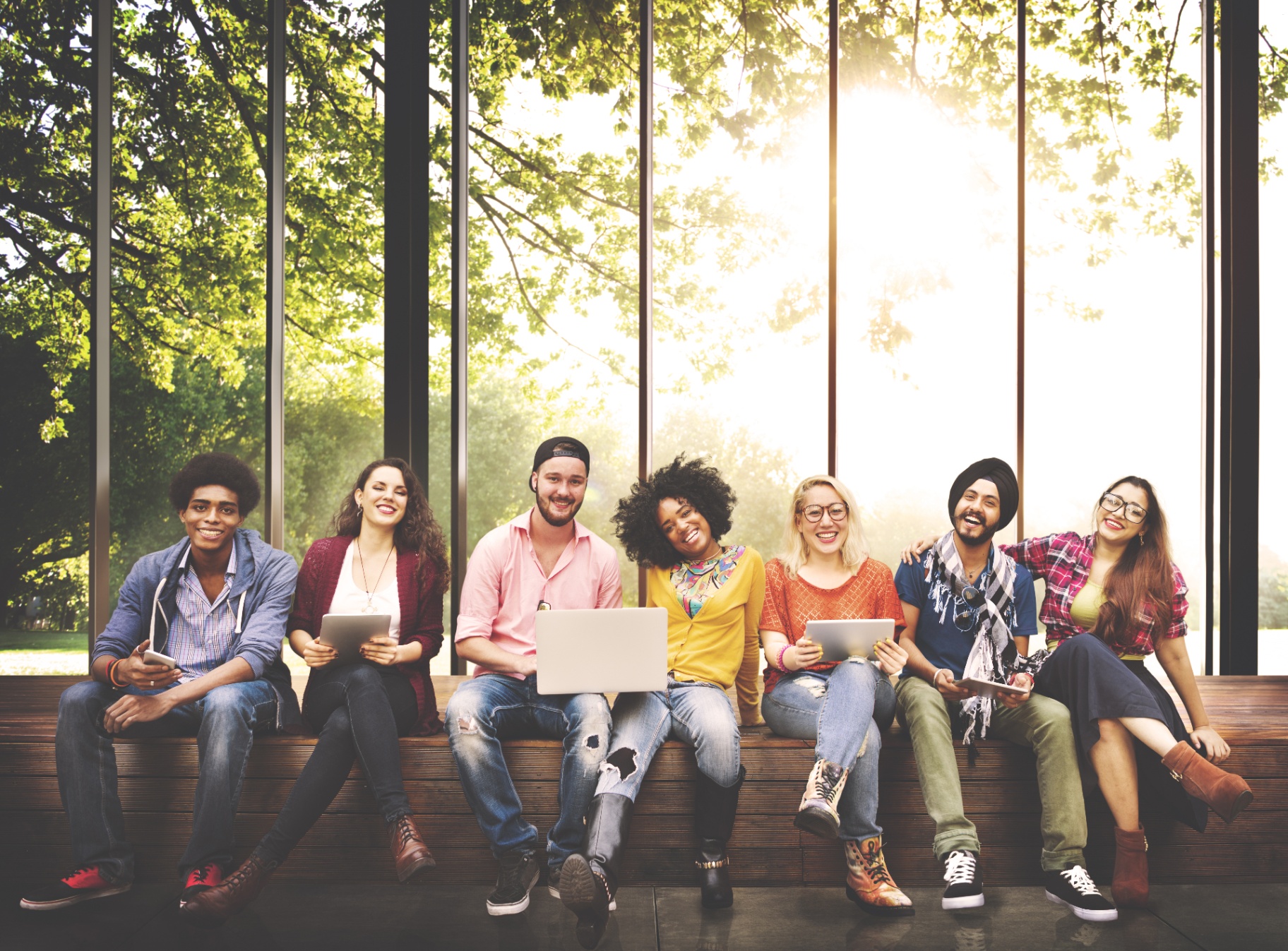 Diverse group of students smiling on a sunlit campus bench